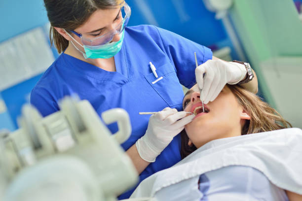people, medicine, stomatology and health care concept - happy female dentist checking patient girl teeth up at dental clinic office